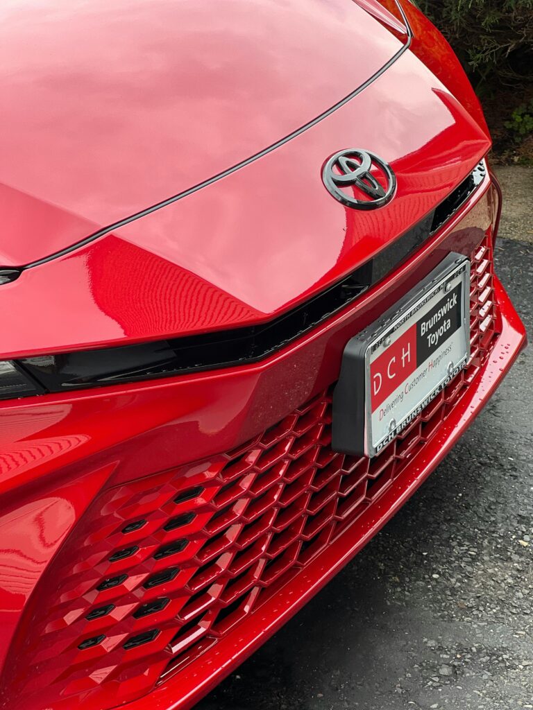 Detailed view of a glossy red car grille showcasing modern design and elegance.
